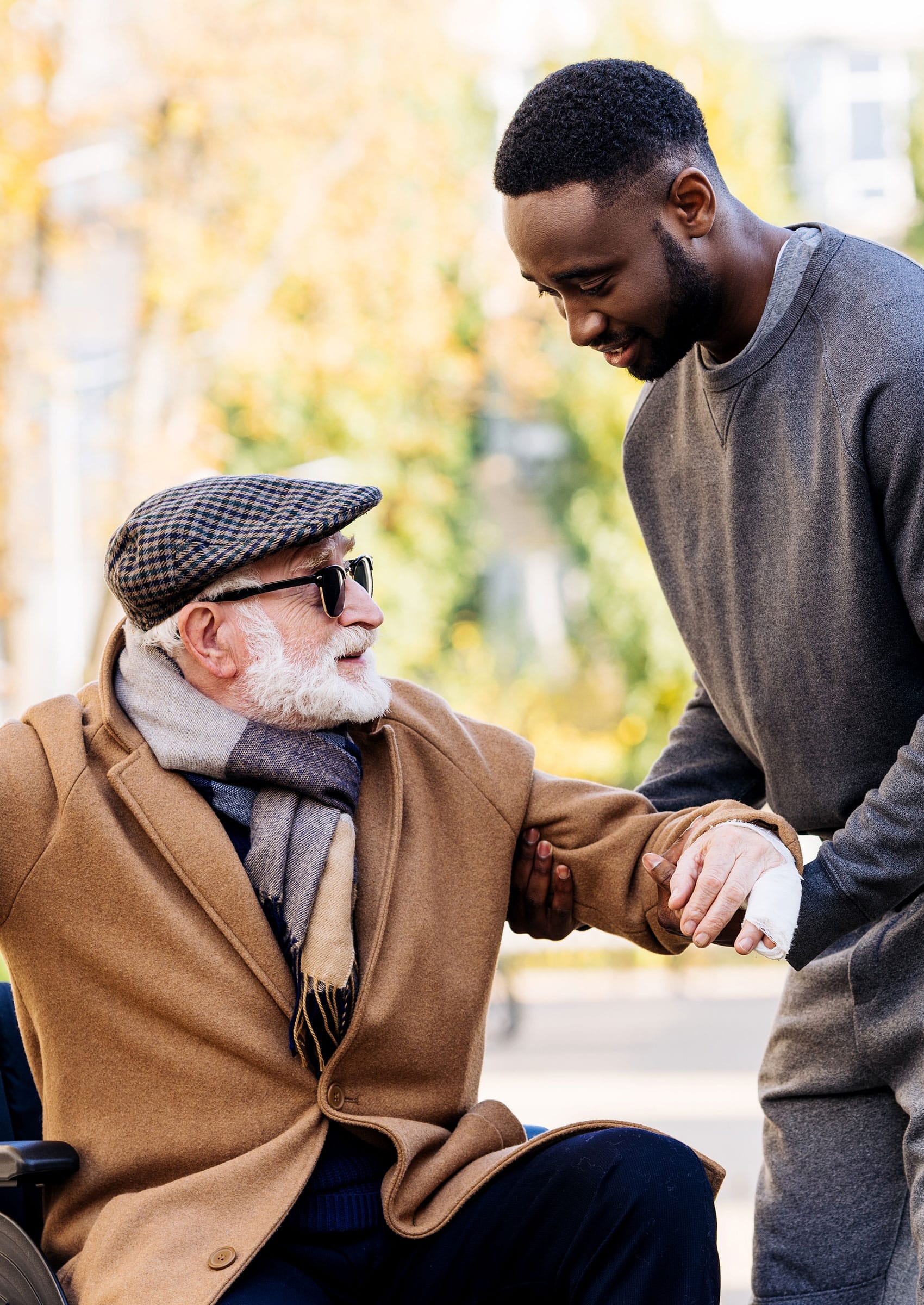 makeup-studio-35 Young man helping senior disabled man to get up from wheelchair on street